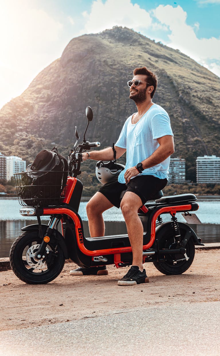 A Man in White Shirt and Black Shorts Sitting on Red E-Bike