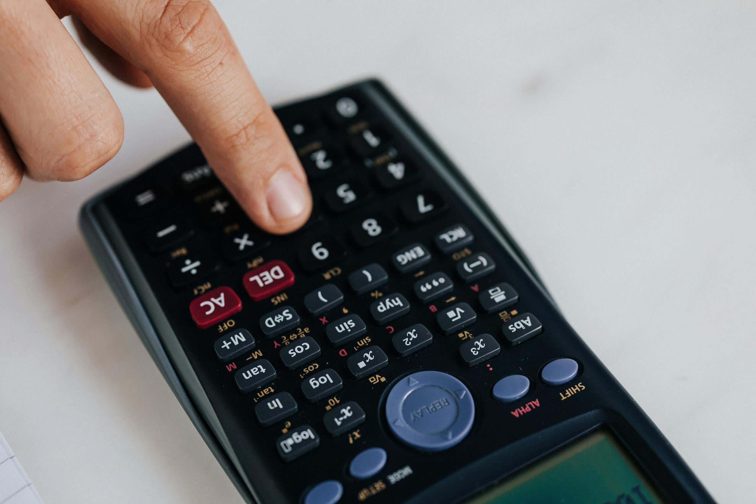 From above of crop anonymous economist calculating on calculator with plastic buttons while making budget on marble table