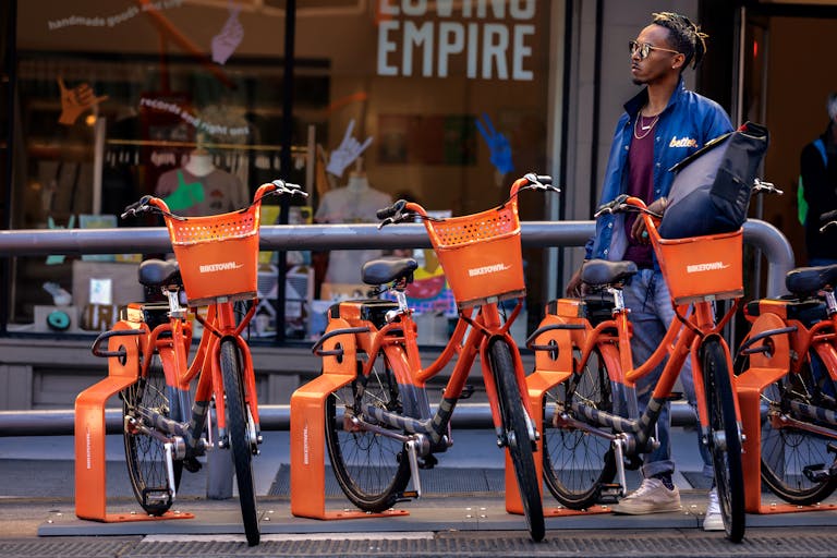 Man Standing Behind Parked Orange Bicycles