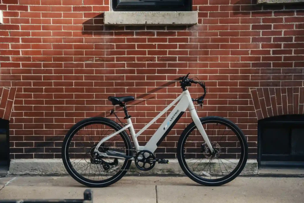 White Lectric XPress Lite commuter electric bike parked in front of a red brick wall