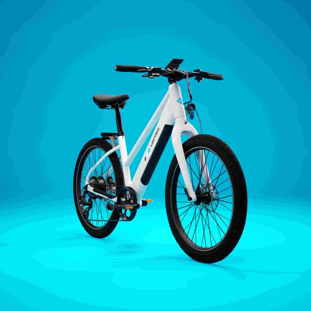 White Lectric XPress Lite electric commuter bike photographed from the front at an angle against a blue studio background